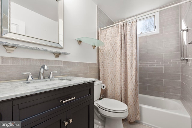 full bathroom with vanity, shower / bathtub combination with curtain, wainscoting, tile walls, and toilet