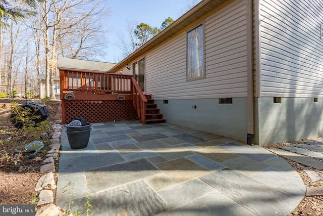 view of side of property featuring crawl space, a deck, and a patio area