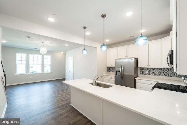 kitchen featuring tasteful backsplash, pendant lighting, light countertops, stainless steel appliances, and a sink