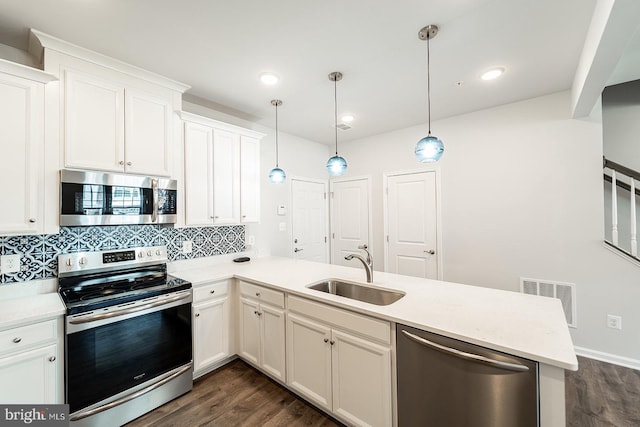 kitchen featuring visible vents, a peninsula, dark wood-style flooring, a sink, and stainless steel appliances