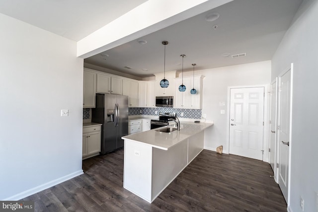 kitchen featuring tasteful backsplash, visible vents, dark wood-type flooring, a peninsula, and stainless steel appliances