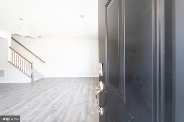 foyer entrance featuring stairway, visible vents, wood finished floors, and an inviting chandelier