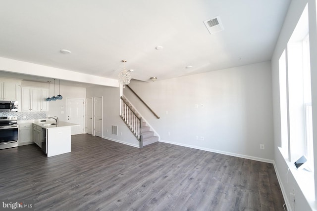 unfurnished living room with stairs, visible vents, and dark wood-style flooring