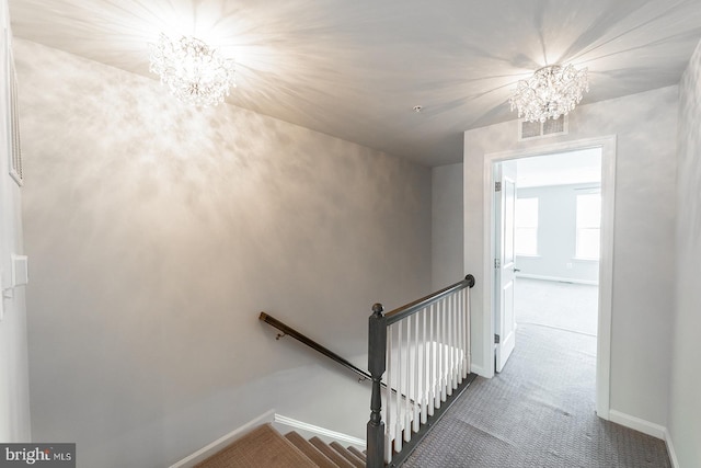 stairs with visible vents, baseboards, a notable chandelier, and carpet