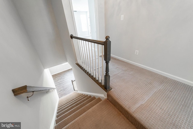 stairway featuring baseboards and carpet