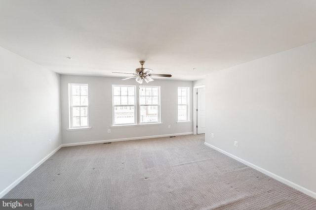 spare room featuring baseboards, light carpet, and a ceiling fan