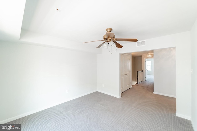 carpeted spare room with visible vents, ceiling fan, and baseboards