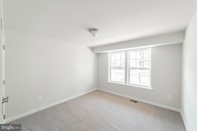 unfurnished room with visible vents, light colored carpet, and baseboards