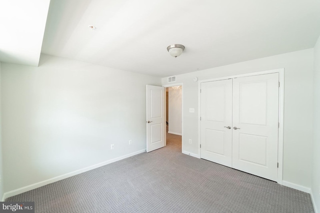 unfurnished bedroom featuring visible vents, carpet, baseboards, and a closet