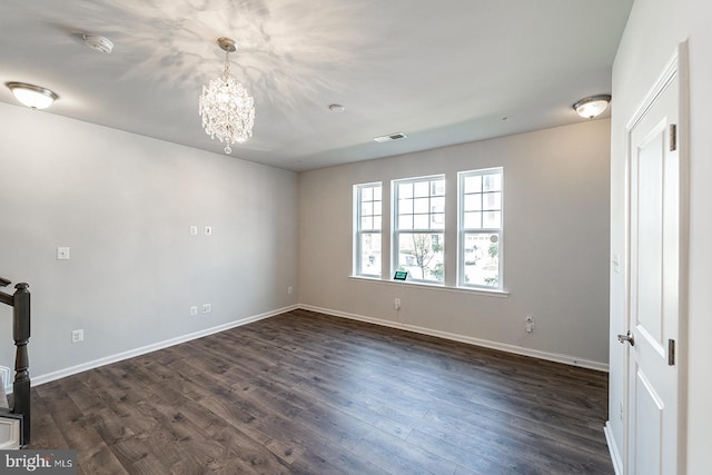 empty room with visible vents, baseboards, an inviting chandelier, and dark wood-style floors