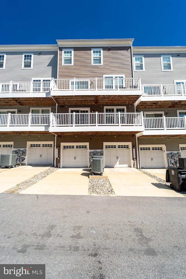 multi unit property with concrete driveway, a garage, and central AC