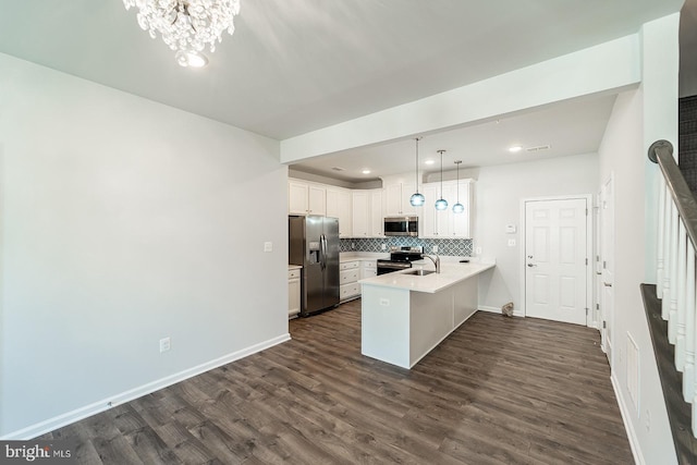 kitchen with backsplash, dark wood-type flooring, appliances with stainless steel finishes, a peninsula, and white cabinetry