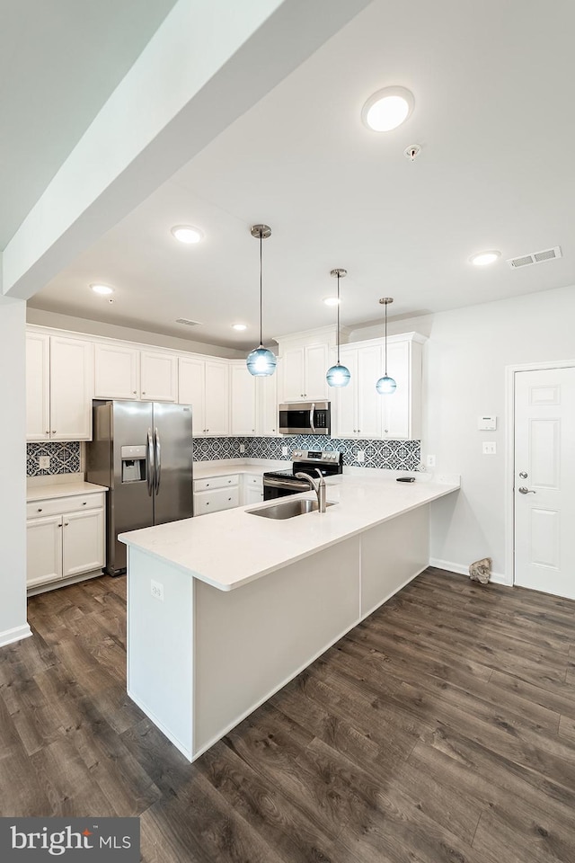 kitchen with visible vents, dark wood finished floors, a peninsula, a sink, and stainless steel appliances