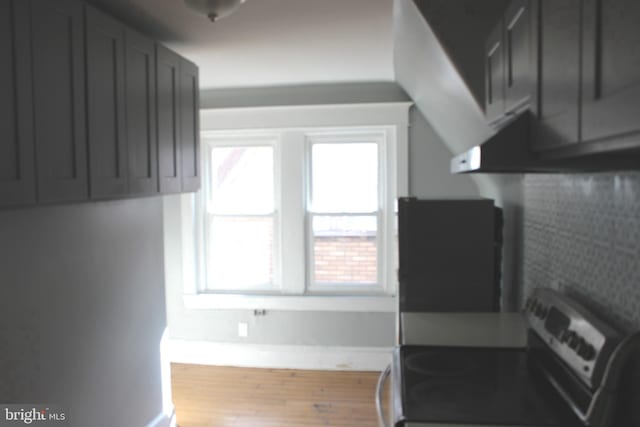 kitchen with gray cabinets, electric stove, wood finished floors, and baseboards