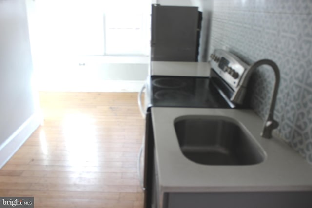 kitchen with baseboards, wood finished floors, and electric stove