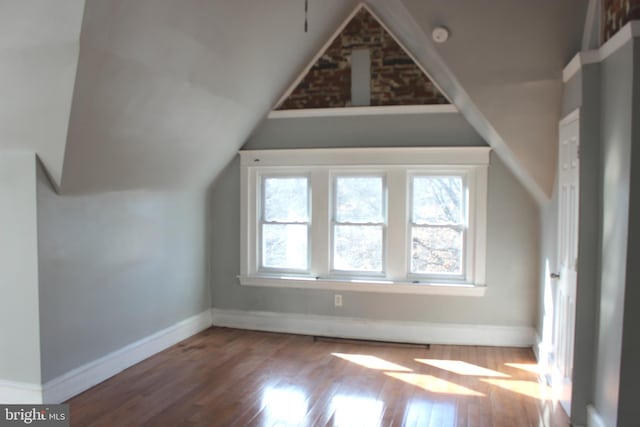 additional living space featuring baseboards, lofted ceiling, and hardwood / wood-style flooring