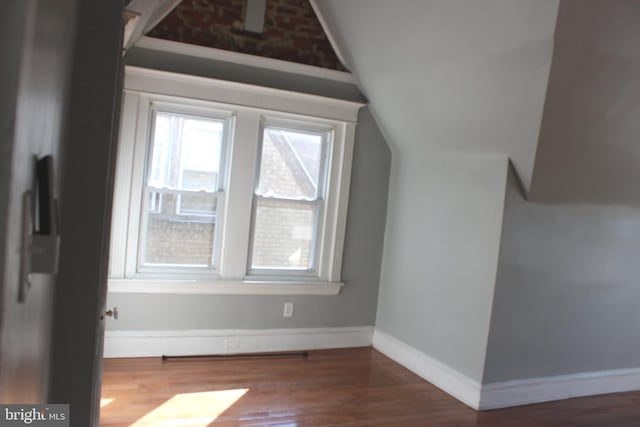 additional living space featuring baseboards, wood finished floors, and vaulted ceiling