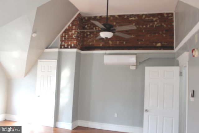 bonus room featuring wood finished floors, baseboards, a wall mounted AC, lofted ceiling, and ceiling fan