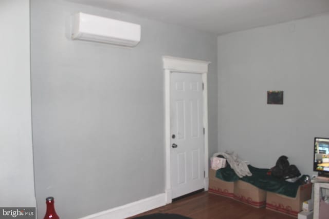 interior space with baseboards, dark wood-type flooring, and a wall mounted AC