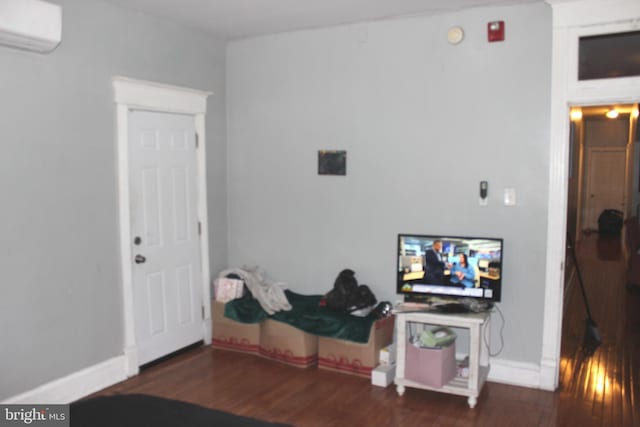 interior space with baseboards, wood finished floors, and a wall unit AC