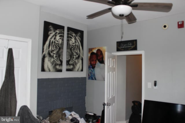 bedroom with a brick fireplace and a ceiling fan