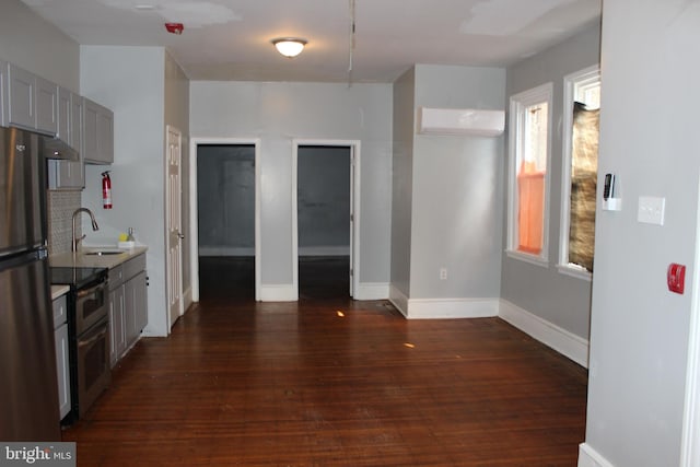 kitchen with a wall mounted AC, dark wood-style flooring, a sink, gray cabinetry, and stainless steel appliances