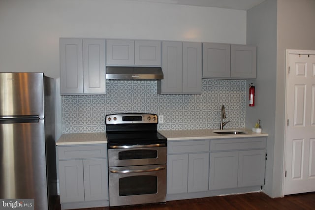 kitchen with under cabinet range hood, gray cabinets, appliances with stainless steel finishes, and a sink