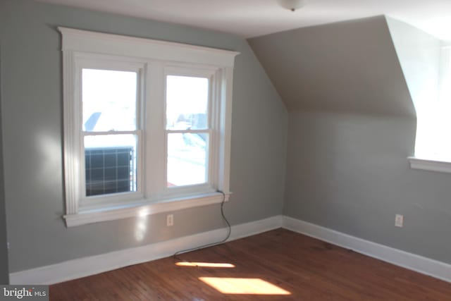 additional living space with plenty of natural light, baseboards, and dark wood-style flooring