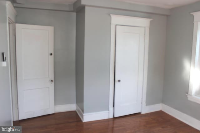 unfurnished bedroom with a closet, baseboards, and wood finished floors