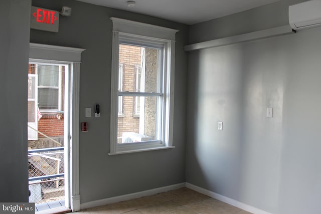 doorway to outside featuring light tile patterned flooring, plenty of natural light, baseboards, and a wall unit AC