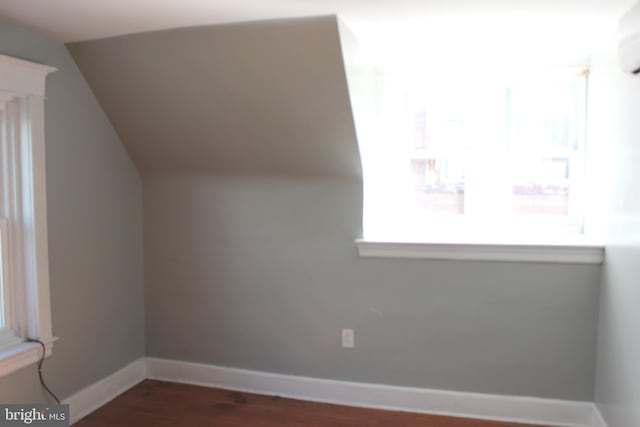 additional living space featuring baseboards, dark wood-style floors, and vaulted ceiling