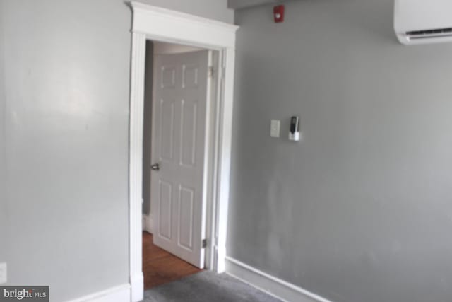 corridor with a wall mounted AC, baseboards, and carpet floors