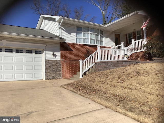 view of front of house featuring brick siding, covered porch, driveway, and a garage