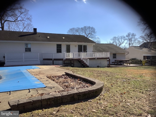 rear view of house with a patio area, a lawn, a wooden deck, and a covered pool