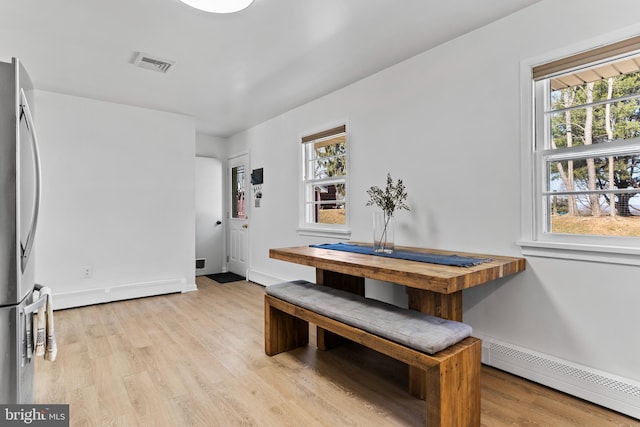 dining area featuring light wood-style flooring, baseboards, visible vents, and baseboard heating