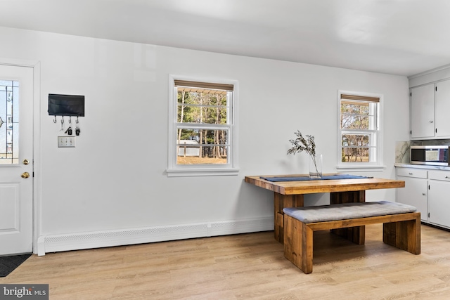 dining area featuring light wood-style floors, baseboards, and a baseboard radiator