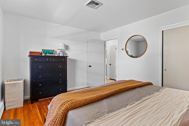 unfurnished bedroom with a closet, visible vents, baseboards, and wood finished floors