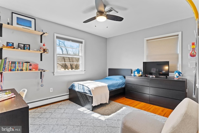 bedroom with a ceiling fan, wood finished floors, visible vents, and baseboard heating