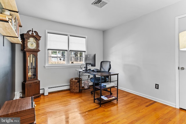 office area featuring a baseboard heating unit, light wood-style flooring, baseboards, and visible vents