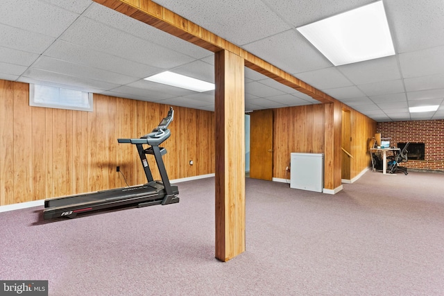 exercise area with a paneled ceiling, carpet floors, baseboards, and wood walls