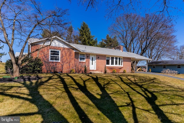 ranch-style home with a chimney, driveway, a front yard, a carport, and brick siding