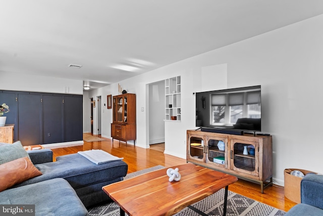 living area with baseboards, visible vents, and light wood finished floors