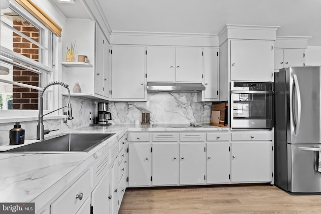 kitchen featuring a sink, under cabinet range hood, white cabinetry, stainless steel appliances, and decorative backsplash