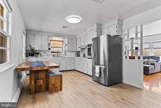 kitchen with visible vents, a baseboard radiator, a sink, appliances with stainless steel finishes, and wood counters