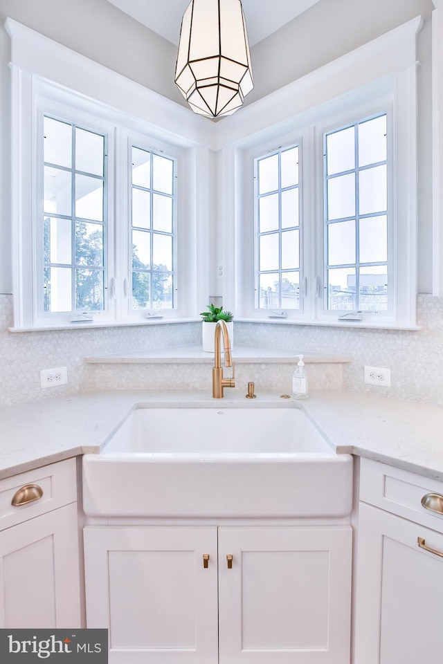 kitchen with white cabinets, light stone countertops, and a sink