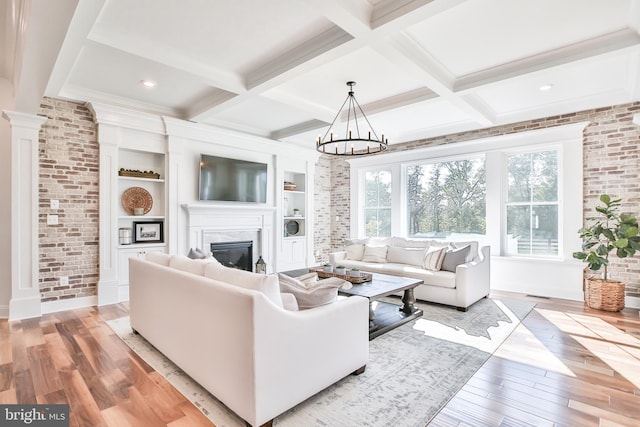 living room featuring a glass covered fireplace, light wood-type flooring, and coffered ceiling