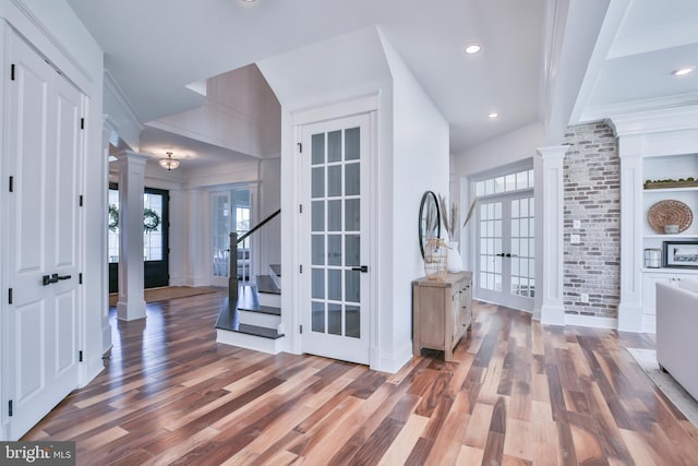 entryway with decorative columns, a healthy amount of sunlight, and wood finished floors