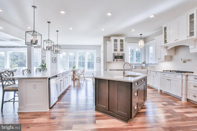 kitchen with a sink, appliances with stainless steel finishes, a center island with sink, and white cabinetry