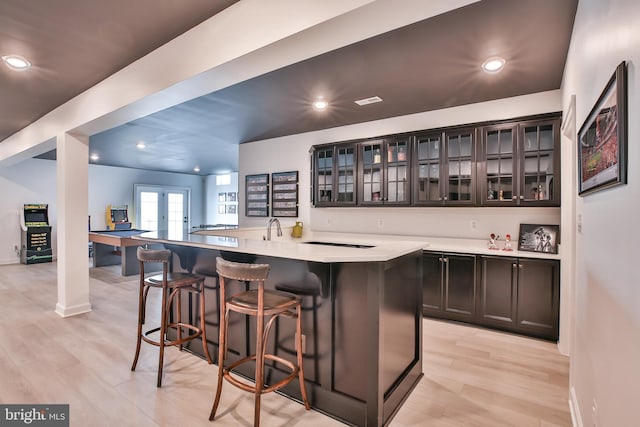 bar featuring a sink, recessed lighting, french doors, light wood finished floors, and baseboards