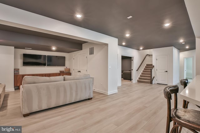 living area featuring visible vents, baseboards, stairway, recessed lighting, and light wood-style flooring